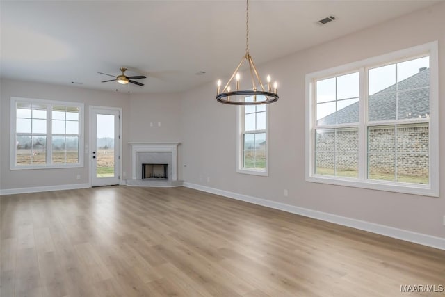 unfurnished living room featuring visible vents, a healthy amount of sunlight, and baseboards