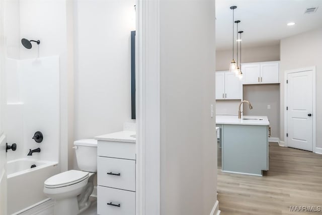 full bathroom featuring visible vents, washtub / shower combination, toilet, wood finished floors, and vanity