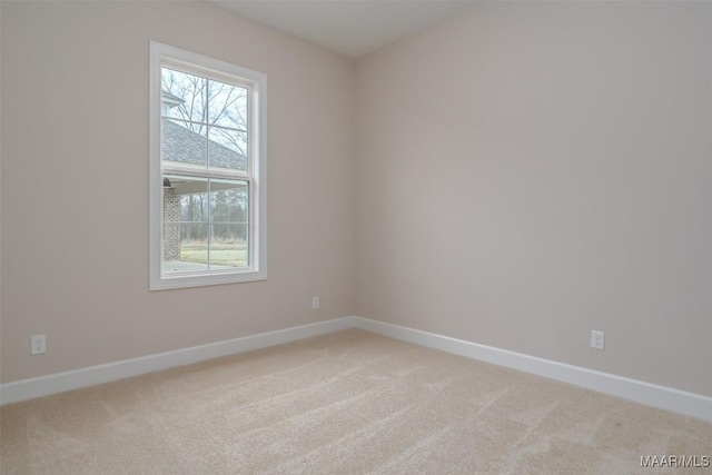 empty room featuring baseboards and light carpet