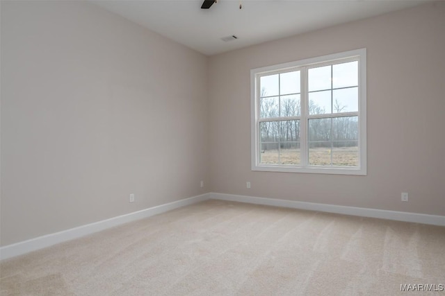 spare room featuring baseboards, light carpet, visible vents, and a ceiling fan