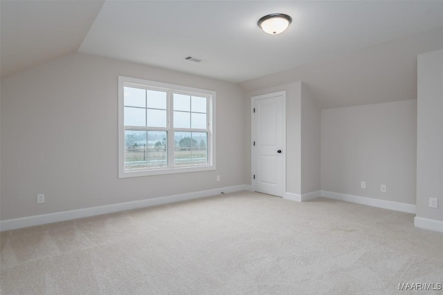 additional living space featuring visible vents, light colored carpet, baseboards, and lofted ceiling