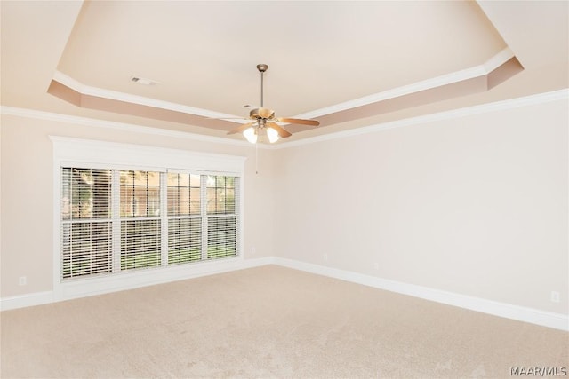 carpeted spare room with ceiling fan, a raised ceiling, and ornamental molding