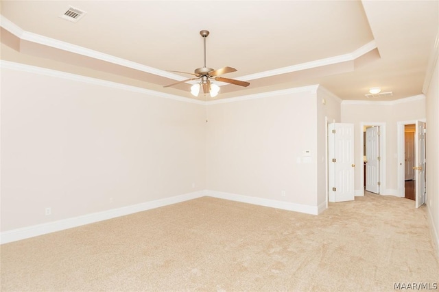 spare room featuring a raised ceiling, ceiling fan, light colored carpet, and ornamental molding