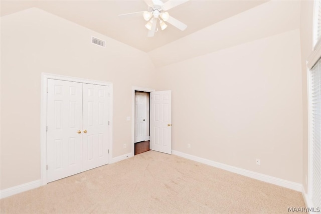 unfurnished bedroom featuring light carpet, a closet, high vaulted ceiling, and ceiling fan