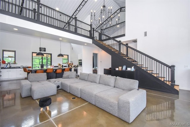 living room featuring sink, a chandelier, and a high ceiling