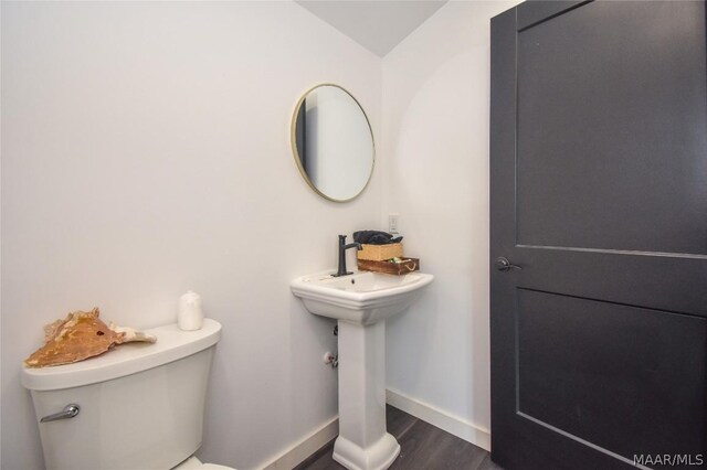 bathroom with toilet, wood-type flooring, and sink