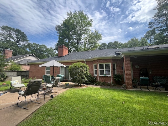 back of house featuring a yard, brick siding, a patio area, and fence