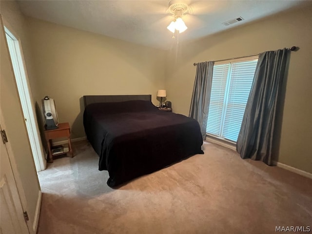 bedroom with a ceiling fan, light colored carpet, visible vents, and baseboards