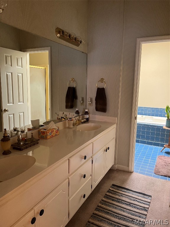 bathroom with tile patterned floors, a garden tub, a sink, and double vanity