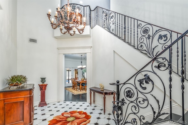 interior space featuring ornamental molding, light hardwood / wood-style floors, a towering ceiling, and an inviting chandelier