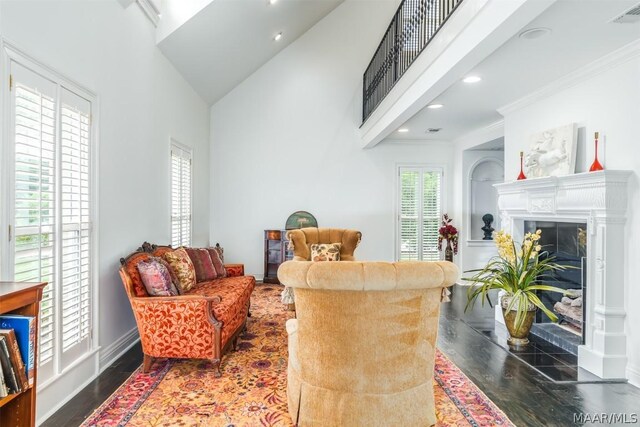 living room with high vaulted ceiling, hardwood / wood-style flooring, a tiled fireplace, and crown molding