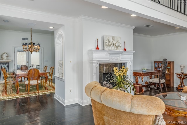 living room with a chandelier, a tiled fireplace, crown molding, dark wood-type flooring, and french doors