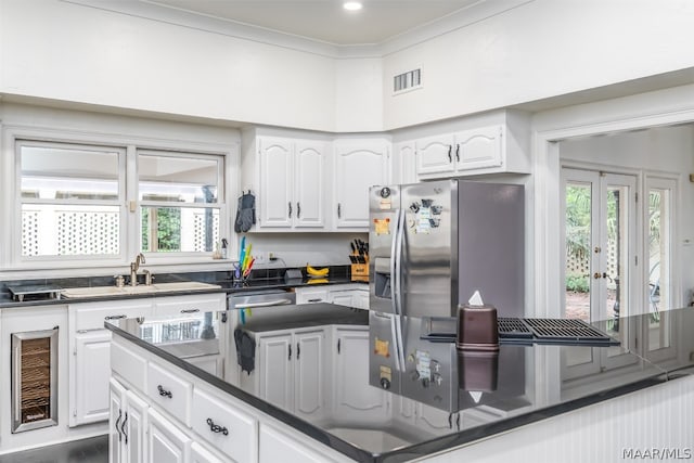 kitchen featuring white cabinetry, french doors, ornamental molding, stainless steel appliances, and sink