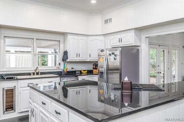 kitchen with visible vents, dishwasher, ornamental molding, white cabinetry, and a sink