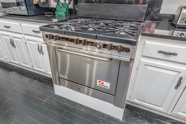 kitchen featuring white cabinetry, premium stove, dark wood-type flooring, and tasteful backsplash