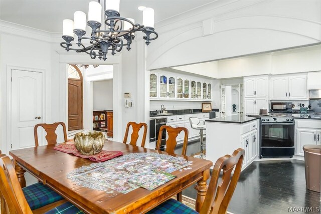 dining space with dark hardwood / wood-style flooring, sink, crown molding, and an inviting chandelier