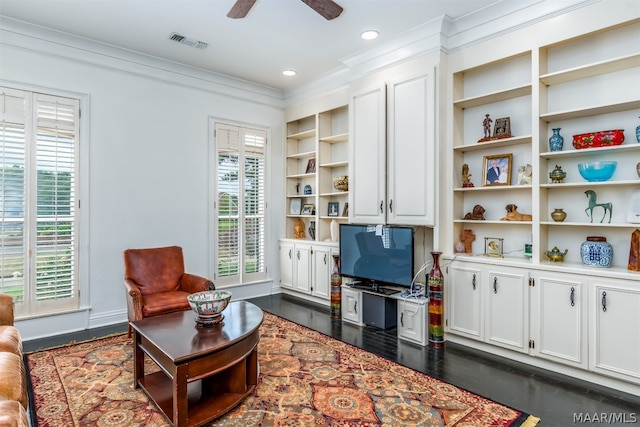 living room featuring dark hardwood / wood-style floors, ceiling fan, built in shelves, and crown molding