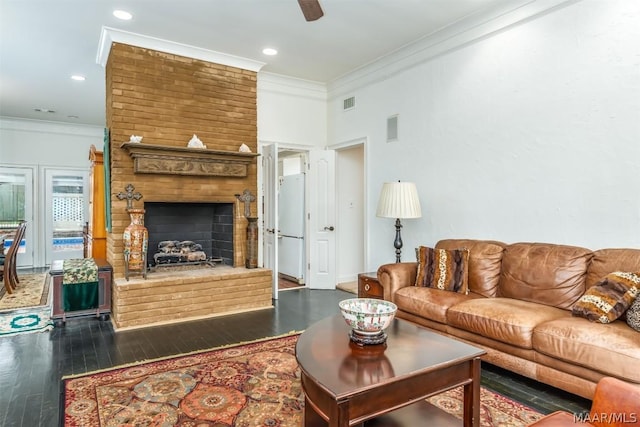 living room with crown molding, a fireplace, visible vents, and wood finished floors