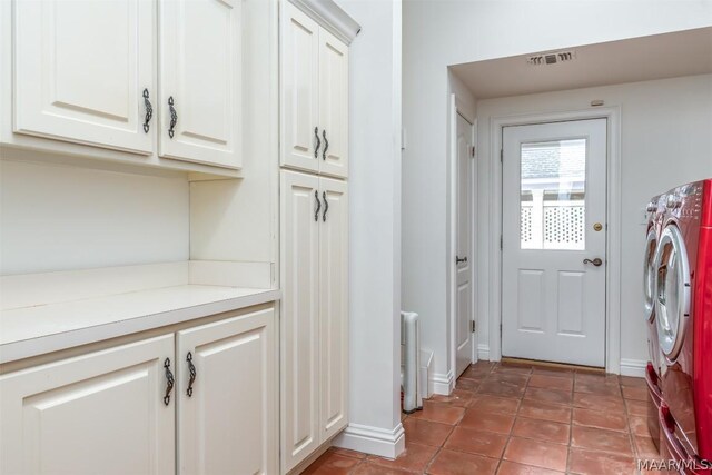 laundry area featuring tile flooring, separate washer and dryer, and cabinets