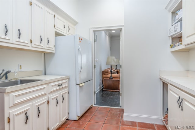 kitchen featuring white cabinetry, ornamental molding, white refrigerator, wood-type flooring, and sink