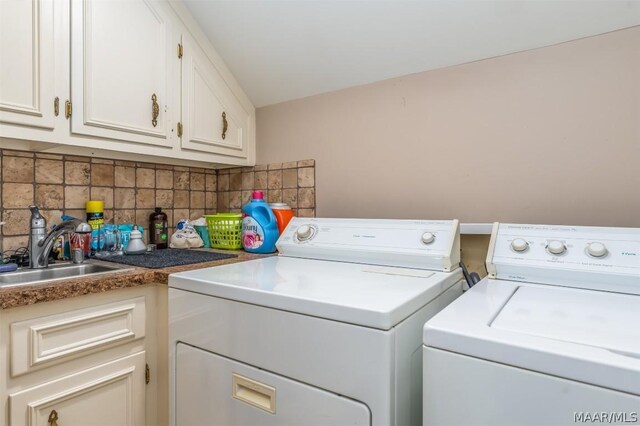 washroom featuring washing machine and dryer, sink, and cabinets