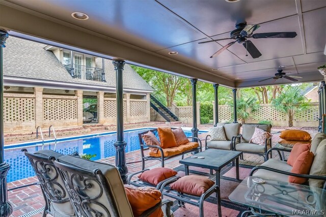 view of terrace with a balcony, an outdoor living space, ceiling fan, and a fenced in pool