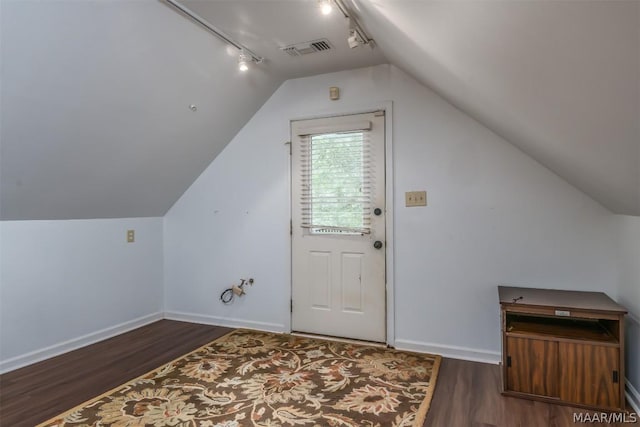 additional living space featuring dark wood-style floors, lofted ceiling, and visible vents