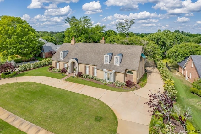 view of front of home featuring driveway, a chimney, a front lawn, and stucco siding