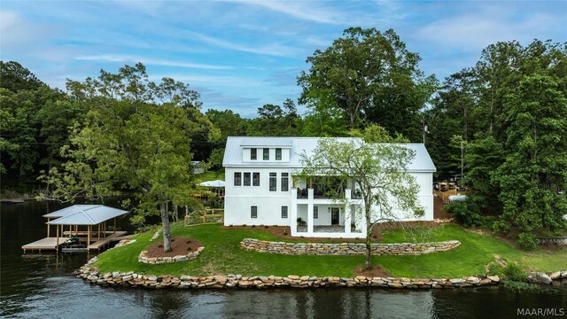 rear view of house featuring a lawn and a water view