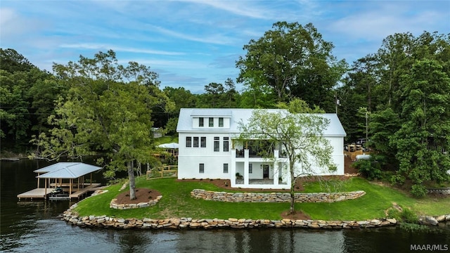 back of house with a water view, a balcony, and a yard