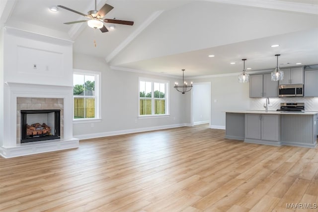 unfurnished living room with a fireplace, light hardwood / wood-style floors, ceiling fan with notable chandelier, and sink