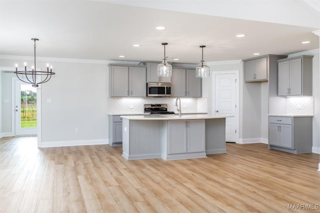 kitchen featuring appliances with stainless steel finishes, backsplash, gray cabinetry, decorative light fixtures, and light hardwood / wood-style floors