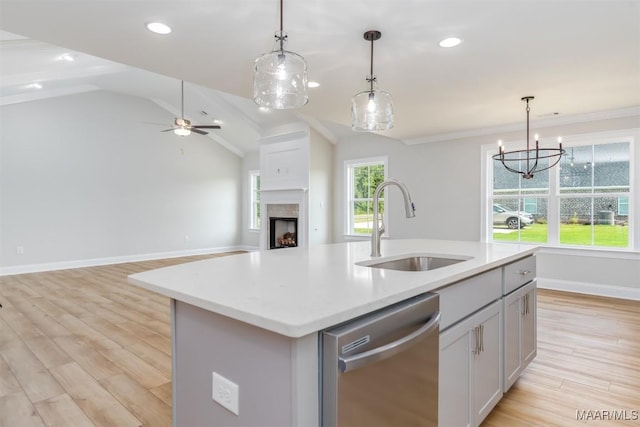 kitchen featuring a kitchen island with sink, sink, vaulted ceiling, stainless steel dishwasher, and decorative light fixtures