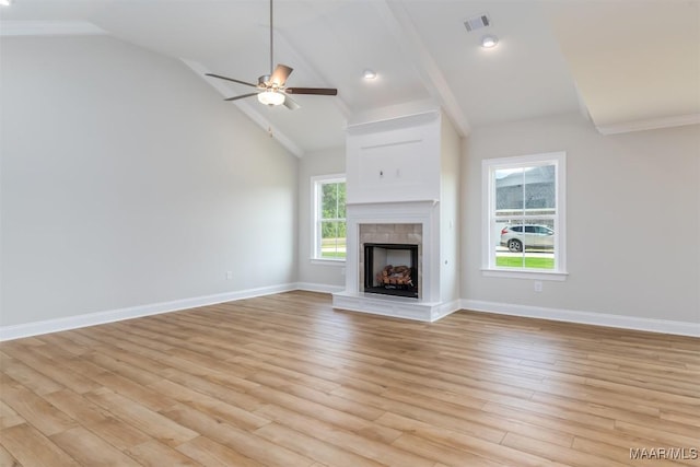 unfurnished living room featuring lofted ceiling with beams, light hardwood / wood-style flooring, ceiling fan, and a tiled fireplace