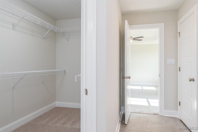 spacious closet with ceiling fan and light colored carpet