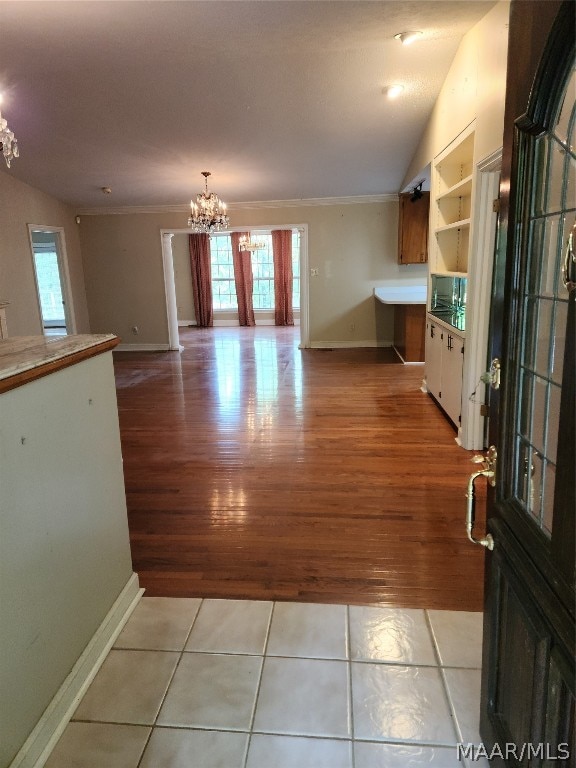 interior space with ornamental molding, built in shelves, hardwood / wood-style floors, and a chandelier