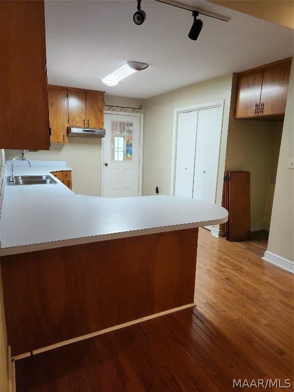 kitchen featuring track lighting, sink, kitchen peninsula, and light wood-type flooring