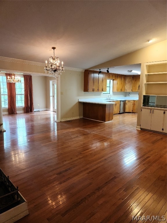 unfurnished living room featuring built in features, ornamental molding, an inviting chandelier, and light wood-type flooring