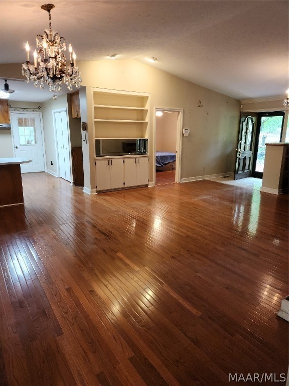 unfurnished living room with an inviting chandelier, built in features, and hardwood / wood-style flooring