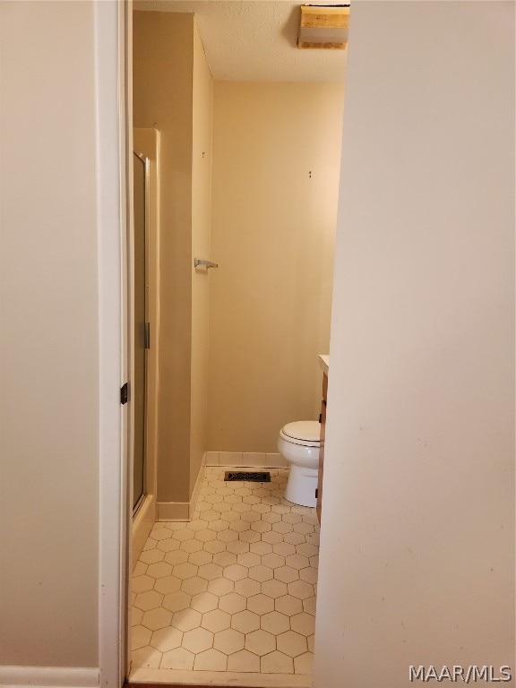 bathroom with tile flooring, an enclosed shower, and toilet