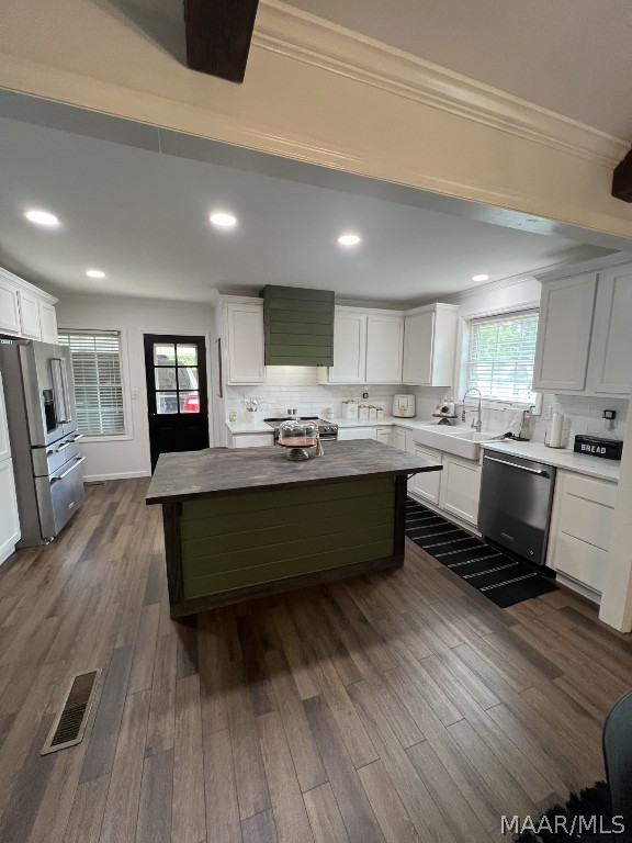 kitchen featuring appliances with stainless steel finishes, white cabinetry, a kitchen island, butcher block counters, and hardwood / wood-style floors