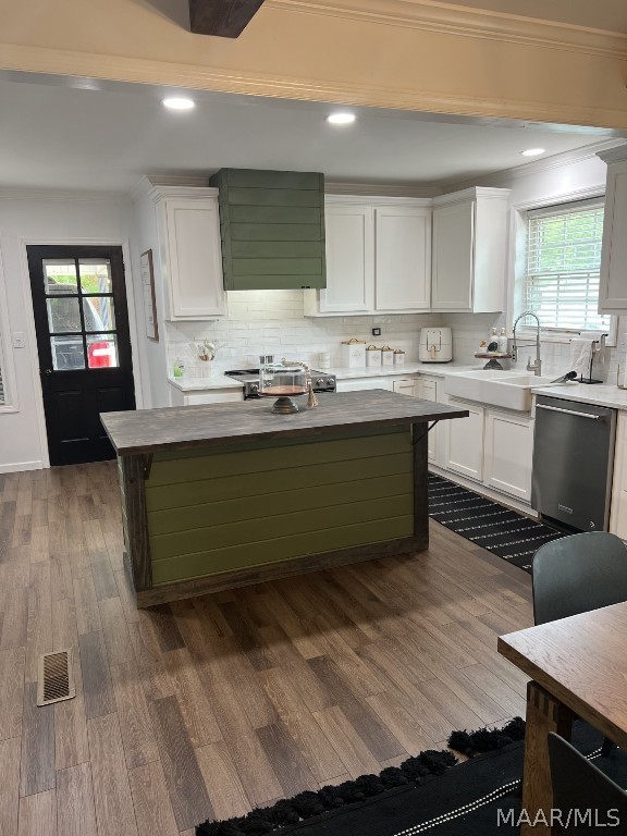 kitchen featuring tasteful backsplash, white cabinets, dishwasher, and hardwood / wood-style flooring