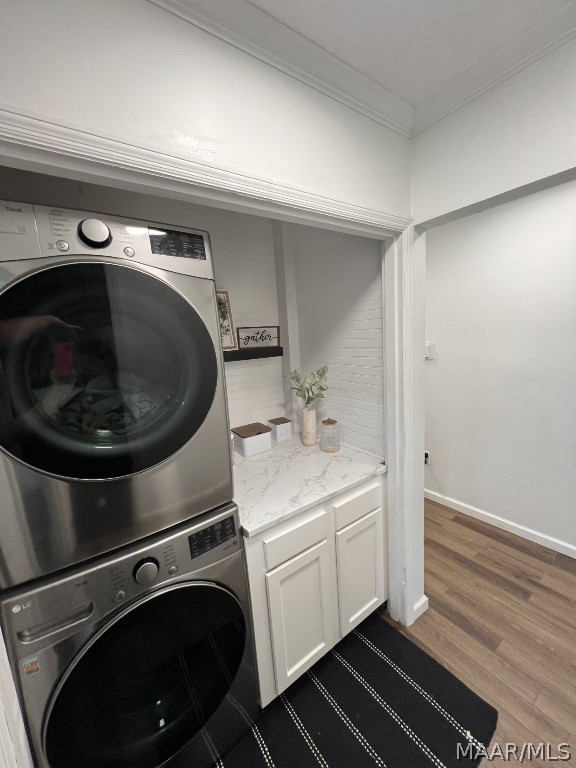 clothes washing area with stacked washer and clothes dryer, ornamental molding, and hardwood / wood-style flooring