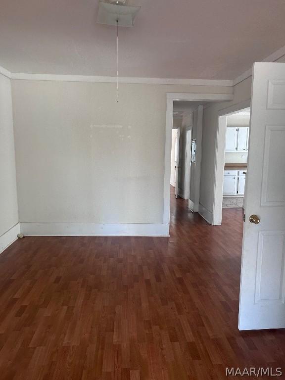 unfurnished room with attic access, crown molding, baseboards, and dark wood-type flooring