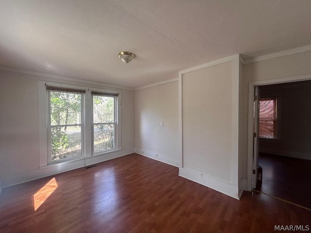 unfurnished room with baseboards, dark wood-style flooring, and crown molding