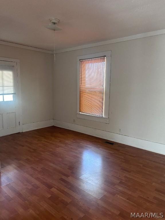 unfurnished room featuring baseboards, visible vents, ornamental molding, and dark wood-type flooring