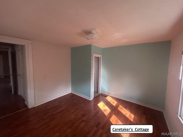 empty room with baseboards and dark wood finished floors