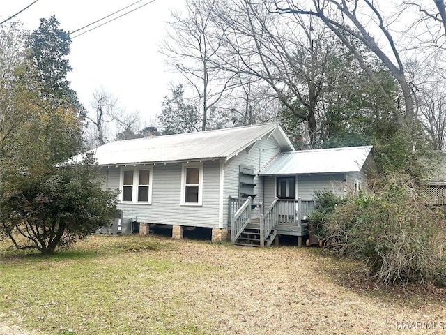 view of front of property featuring a front yard, cooling unit, and metal roof