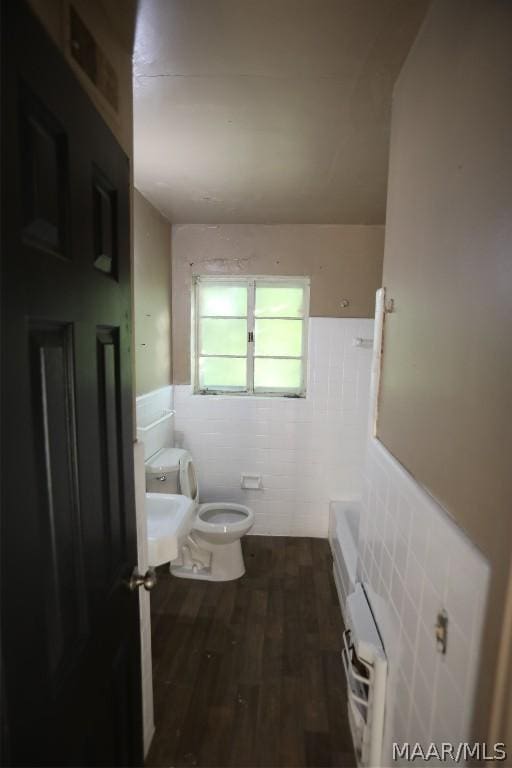 bathroom with toilet, tile walls, a washtub, and hardwood / wood-style floors