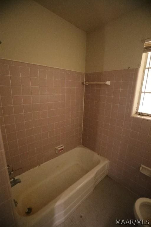 bathroom featuring toilet, tile patterned floors, and tile walls